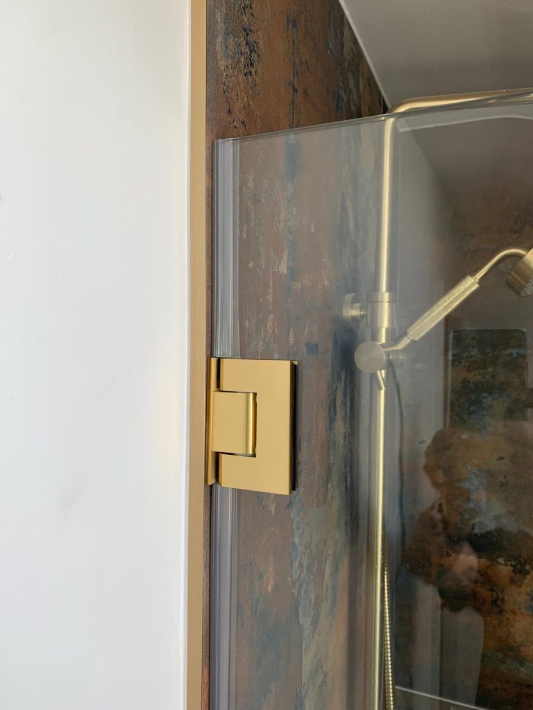 Brushed gold wall bracket fitted to bespoke shower glass panel