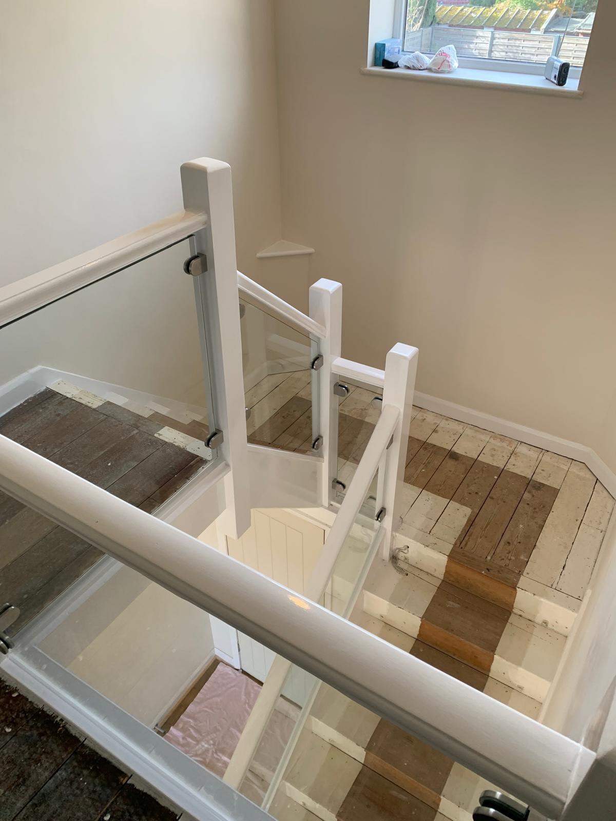 Modern glass balustrade on white-painted wooden staircase installed by CS Glaziers Chester”