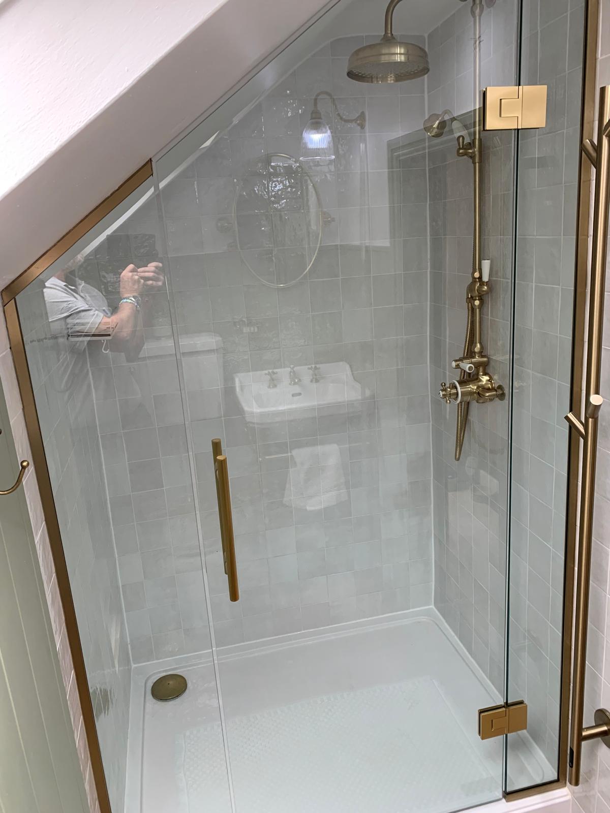 Bespoke glass shower enclosure with 10mm clear toughened glass and brushed brass hardware.