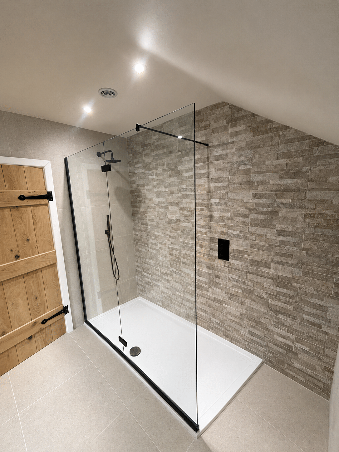Modern clear glass shower screen with black fittings and a spacious white shower tray