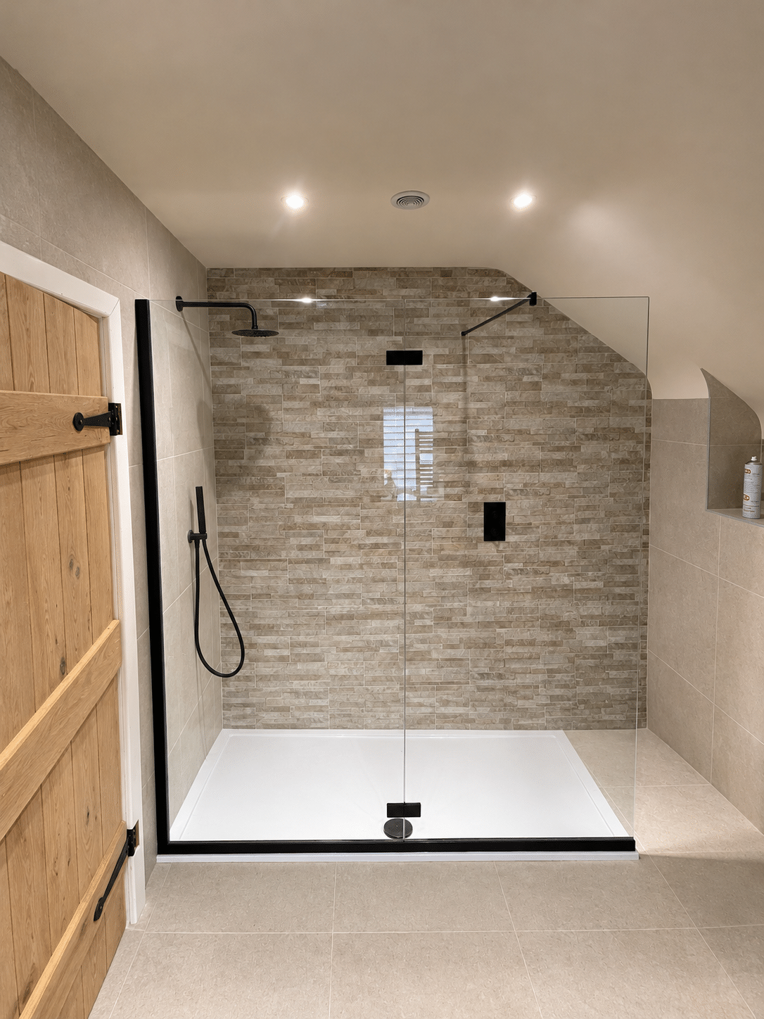 Modern clear glass shower screen with black fittings and a spacious white shower tray